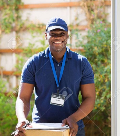 handsome african american delivery man with a parcel standing at the door